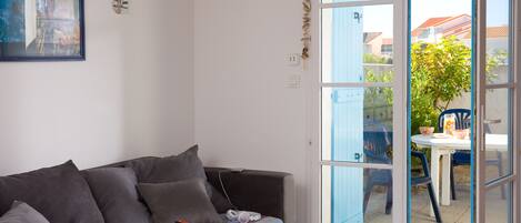 Ein Zimmer mit einer Couch, einem Tisch und Blick ins Freie.