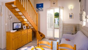 A wooden staircase leading to a loft bedroom with a bed and a window.
