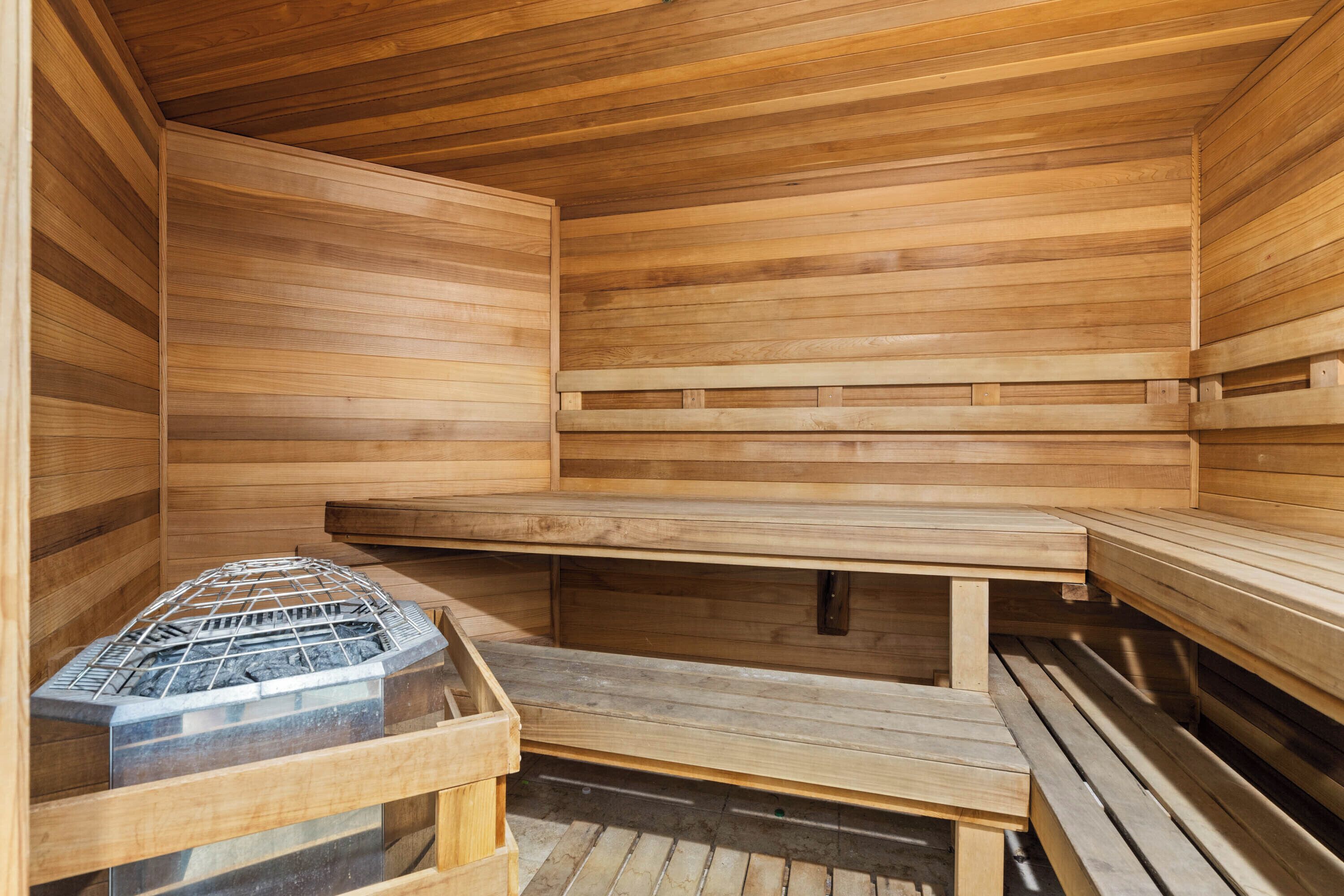 A sauna with wooden benches and a metal grate for the sauna stones.