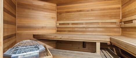 A sauna with wooden benches and a metal grate for the sauna stones.