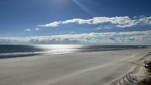 A beach with a clear sky, calm sea, and a distant shoreline. - Saltwater+Sunsets: 2 King bdrms/2ba Oceanfront Escape Awaits! (Gulf Shores)