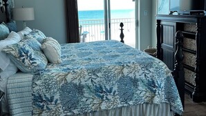 A bedroom with a large bed, a ceiling fan, a TV, and a view of the ocean. - Saltwater+Sunsets: 2 King bdrms/2ba Oceanfront Escape Awaits! (Gulf Shores)