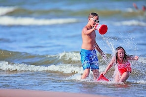 Two children playing in the water at the beach.