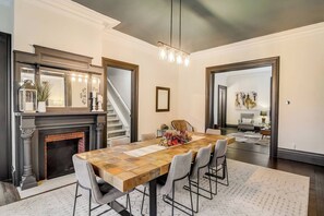 A dining room with a wooden table, six chairs, a fireplace, and a staircase. - Old Plat Homestead -pool & walk to beach (Huron)