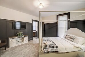 A bedroom with a bed, a TV, a desk, and a wardrobe. - Old Plat Homestead -pool & walk to beach (Huron)