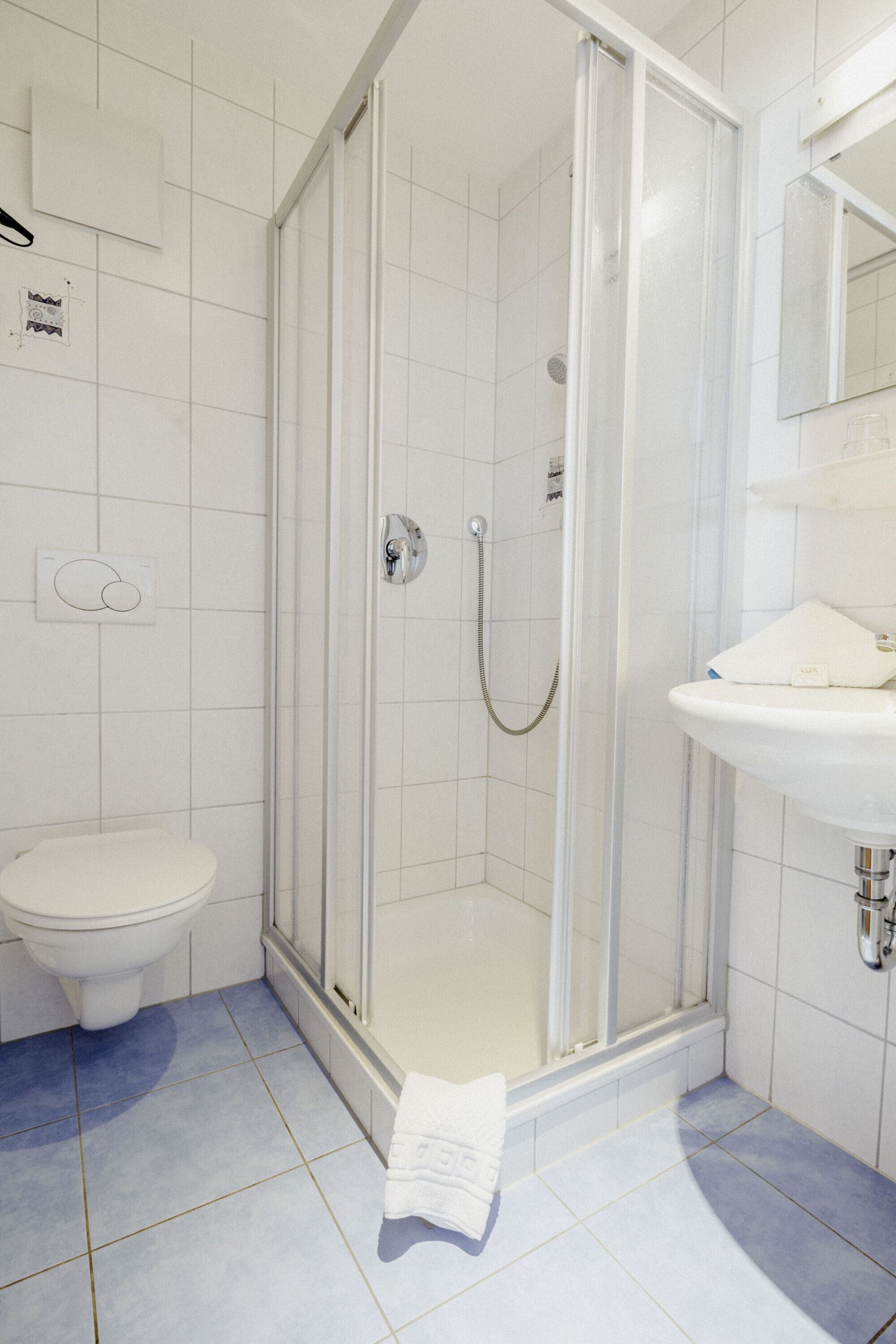 Un baño con cabina de ducha de vidrio, un lavabo blanco y un inodoro.