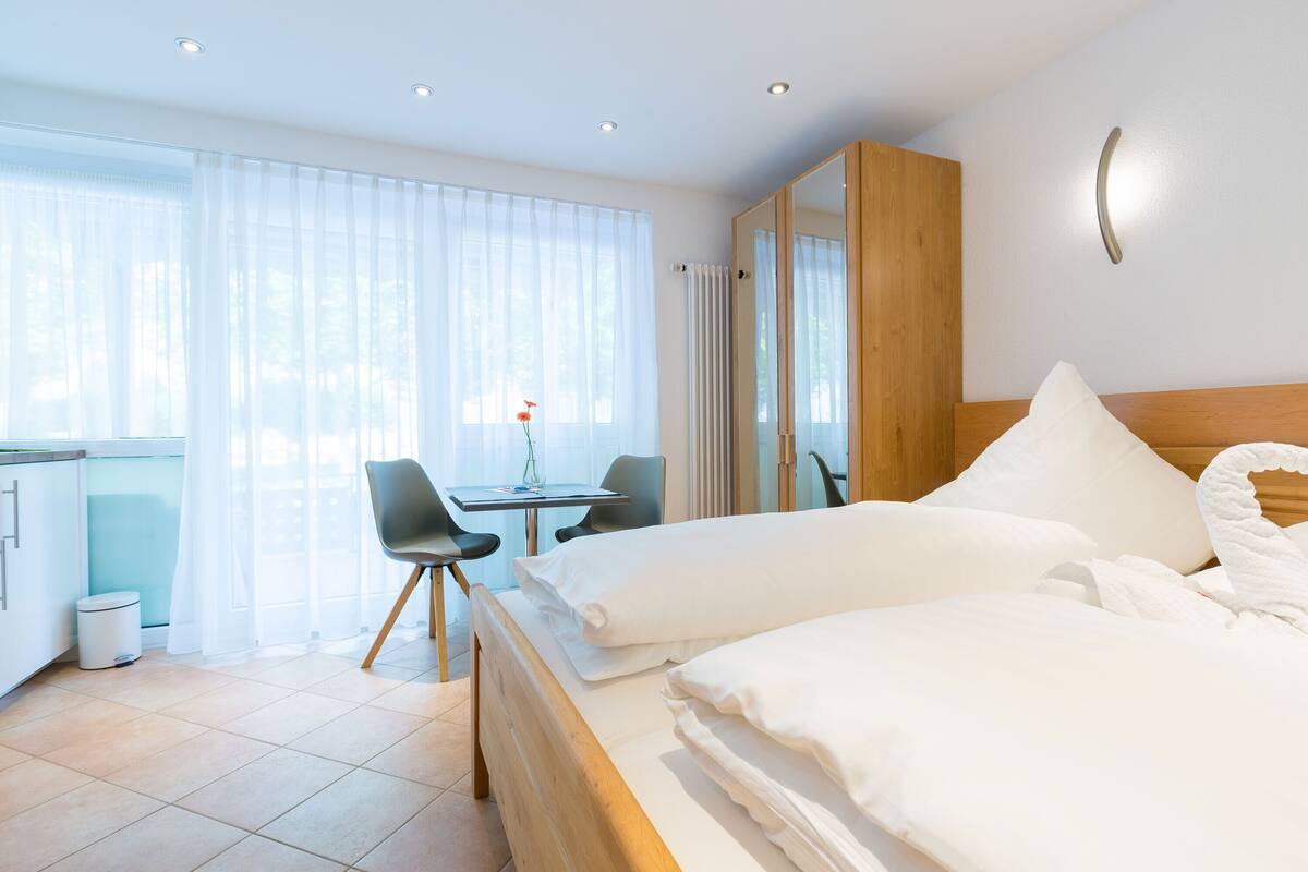 A hotel room with a bed, a desk, and a chair.