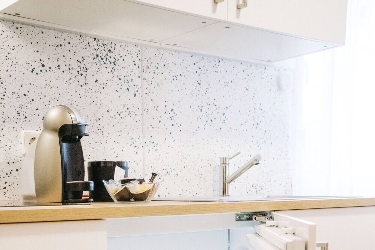 A kitchen with a built-in oven, a refrigerator, and a coffee maker on the countertop.