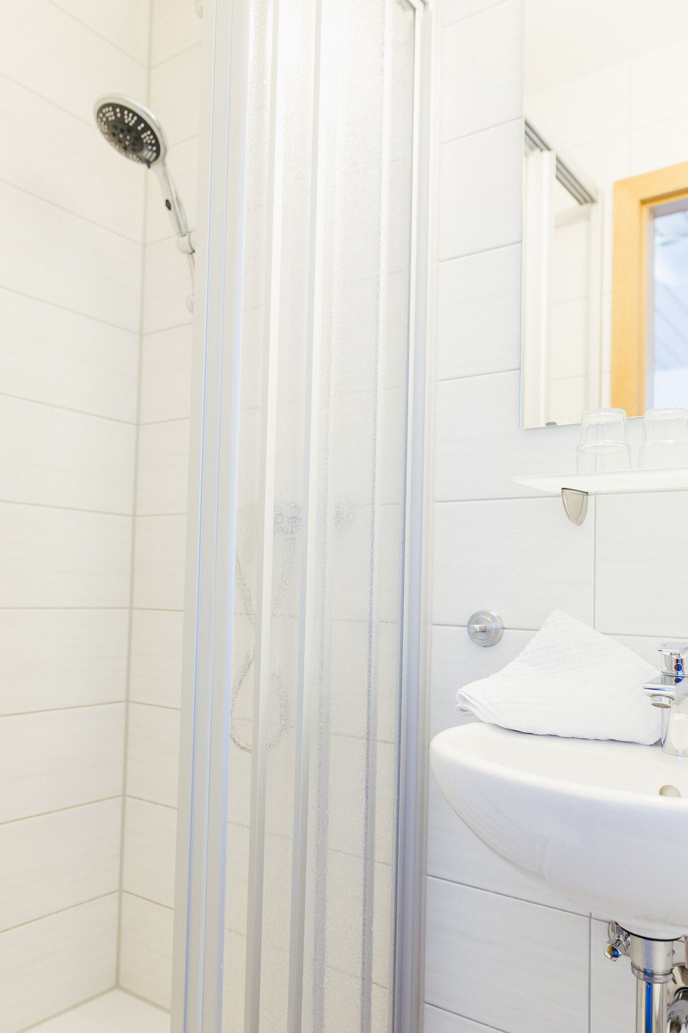 A bathroom with a shower, a sink, and a mirror.