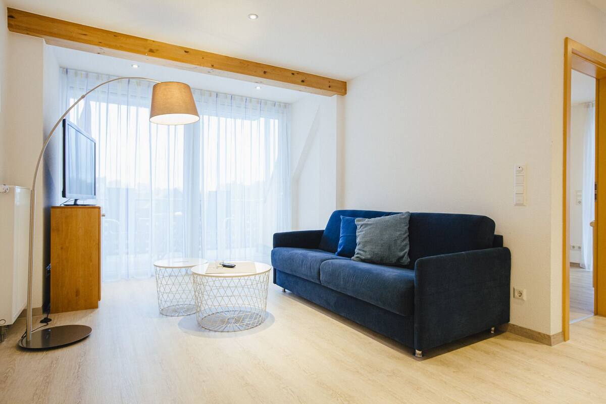 A modern living room with a sofa, a floor lamp, and a small round table.