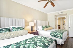A hotel room with two beds, a ceiling fan, a nightstand with a lamp, and a door leading to a bathroom. - Honua Kai | Ocean View 2 BR | Wrap Around Lanai | Car Incl. w/ 6+ Nights | HKK-309 by KBM (Lahaina)