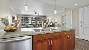 A kitchen with granite countertops, wooden cabinets, stainless steel appliances, and pendant lighting. - Honua Kai | Ocean View 2 BR Sleeps 8 | Car Incl. w/ 6+ Nights | HKK-309 by KBM (Lahaina)