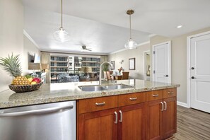 A modern kitchen with granite countertops, stainless steel appliances, and wooden cabinets. - Honua Kai | Ocean View 2 BR | Wrap Around Lanai | Car Incl. w/ 6+ Nights | HKK-309 by KBM (Lahaina)
