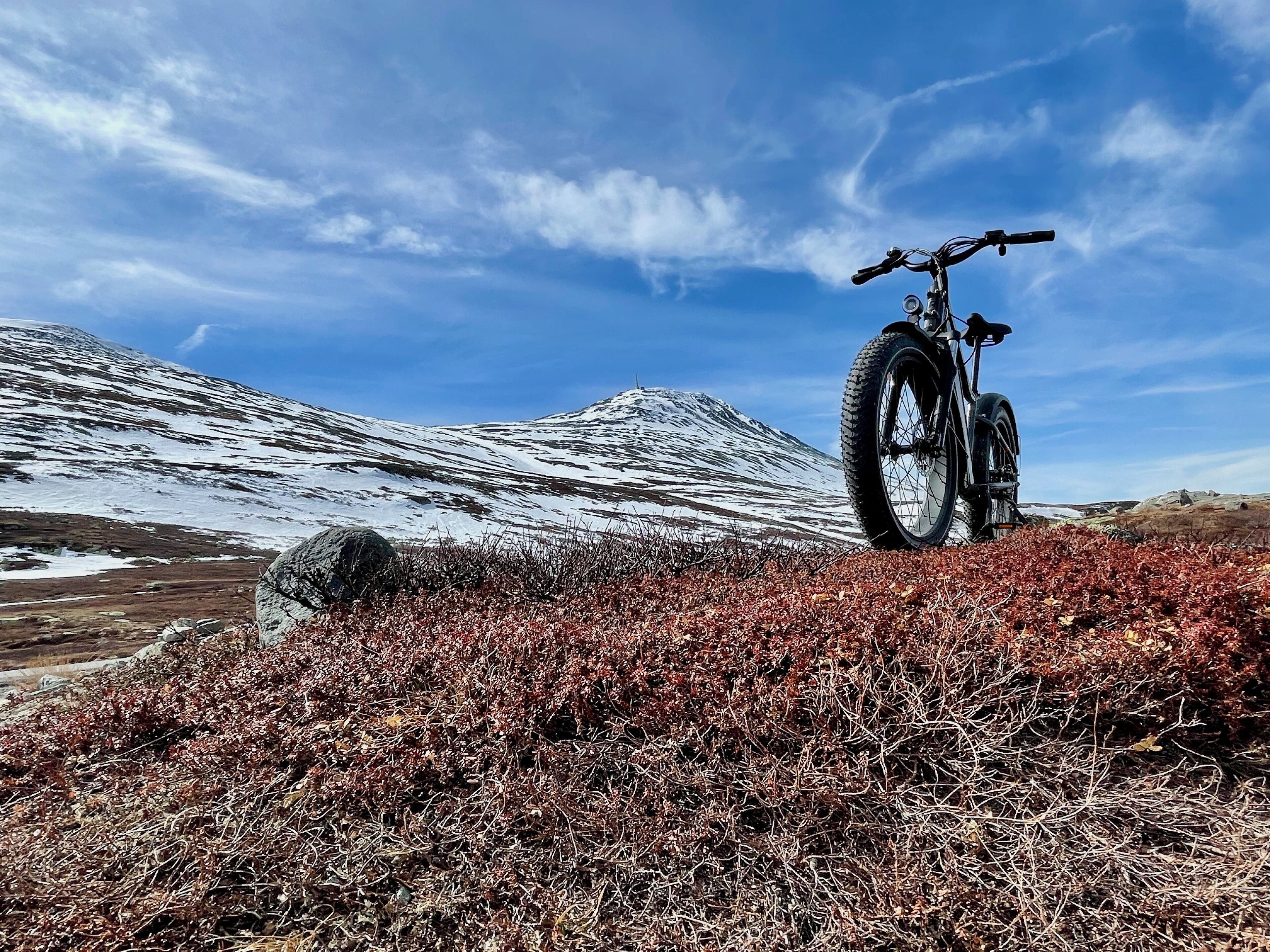 A mountain bike on a rocky terrain with snow-capped mountains in the background.