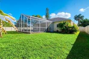 Enjoy the expansive outdoor space with a glass roof, perfect for relaxation and activities, surrounded by lush vegetation and a well-manicured lawn.