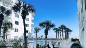 A modern hotel with a pool area, surrounded by palm trees and well-maintained landscaping. - 1BR/1.5BA retreat with direct beach access (Orange Beach)