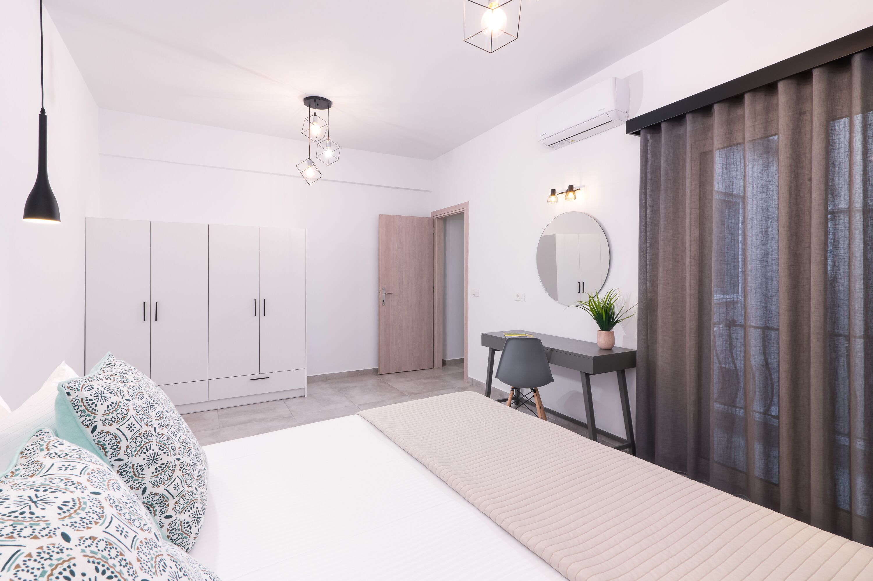 Une chambre moderne avec un lit, une armoire, un bureau et une grande fenêtre avec des rideaux.