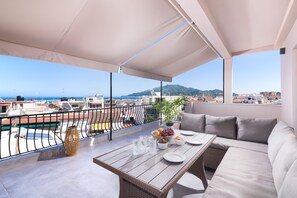A balcony with a view of the sea and mountains, furnished with a sofa, table, and dining setup. - Lithies Zante Living (Zakynthos)