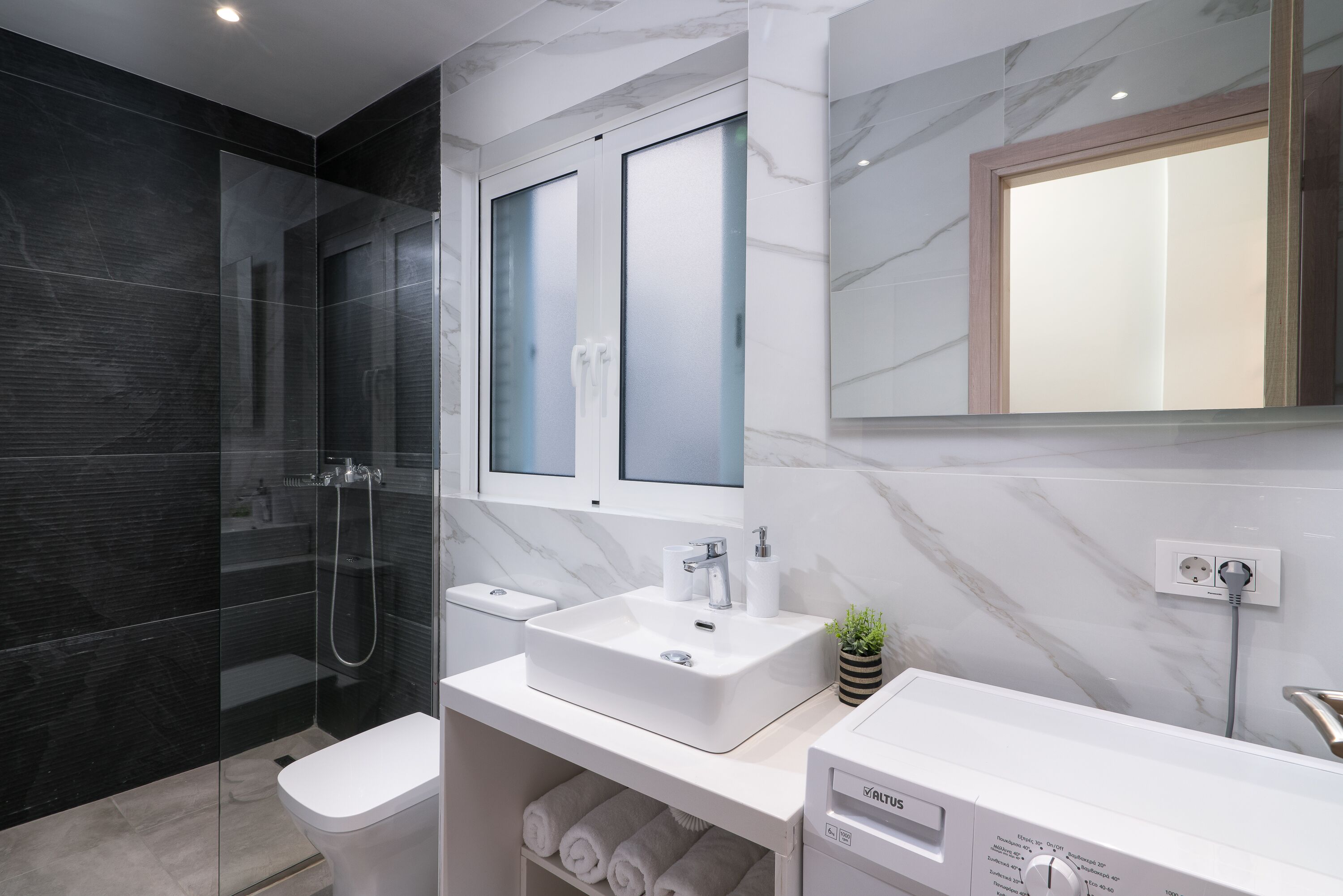 Une salle de bain moderne avec une douche à parois de verre, un lavabo blanc et des toilettes intégrées.