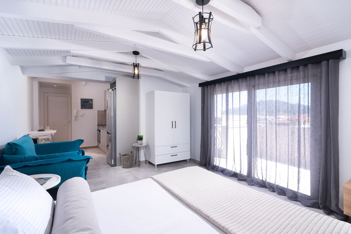 A modern hotel room with a large bed, a sofa, a desk, and a wardrobe.