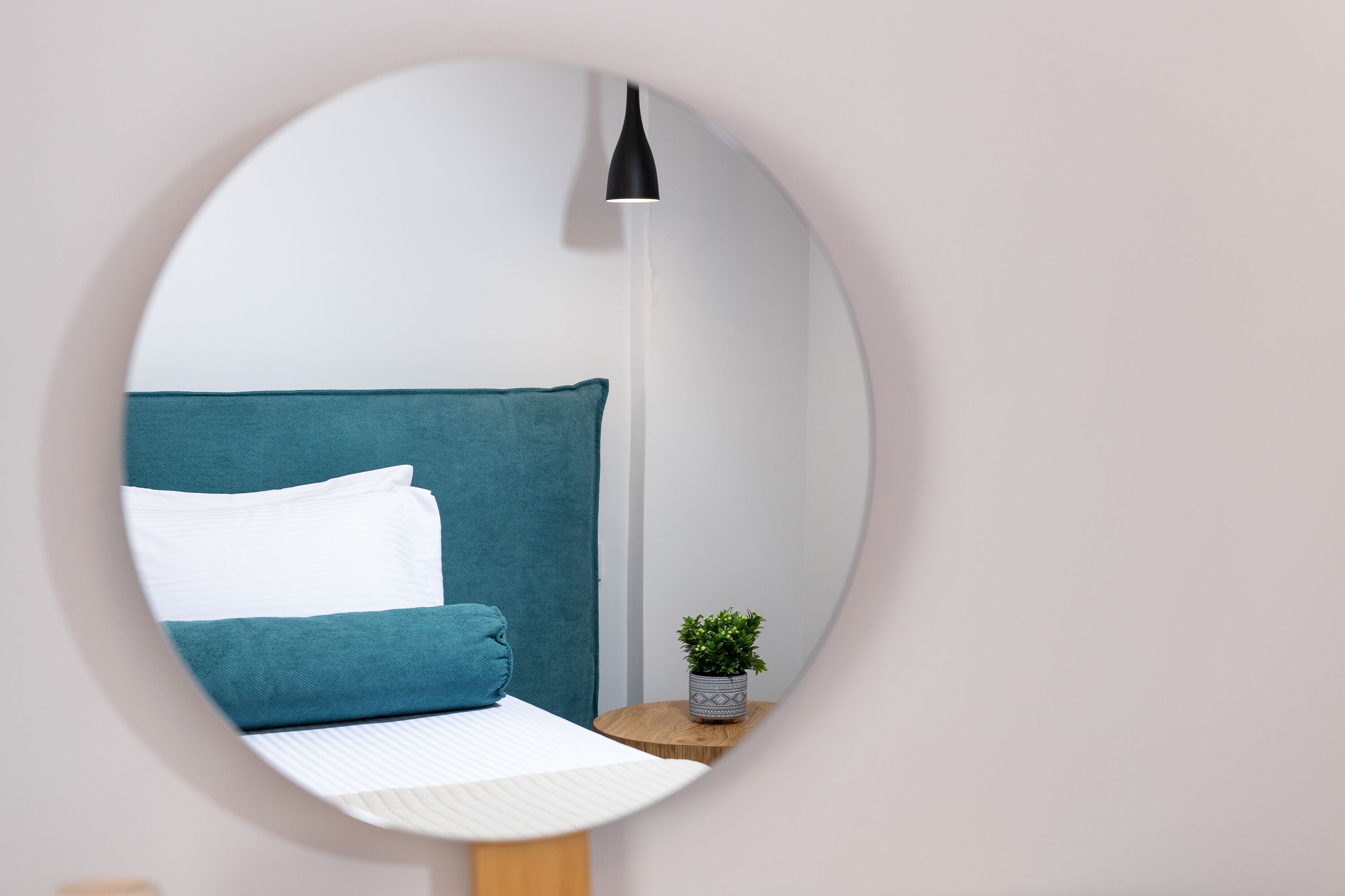 Une chambre à coucher avec un lit, des oreillers, une table de chevet avec une plante et une lampe sur pied.