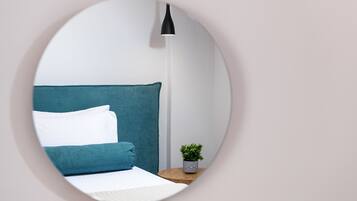 Une chambre à coucher avec un lit, des oreillers, une table de chevet avec une plante et une lampe sur pied.