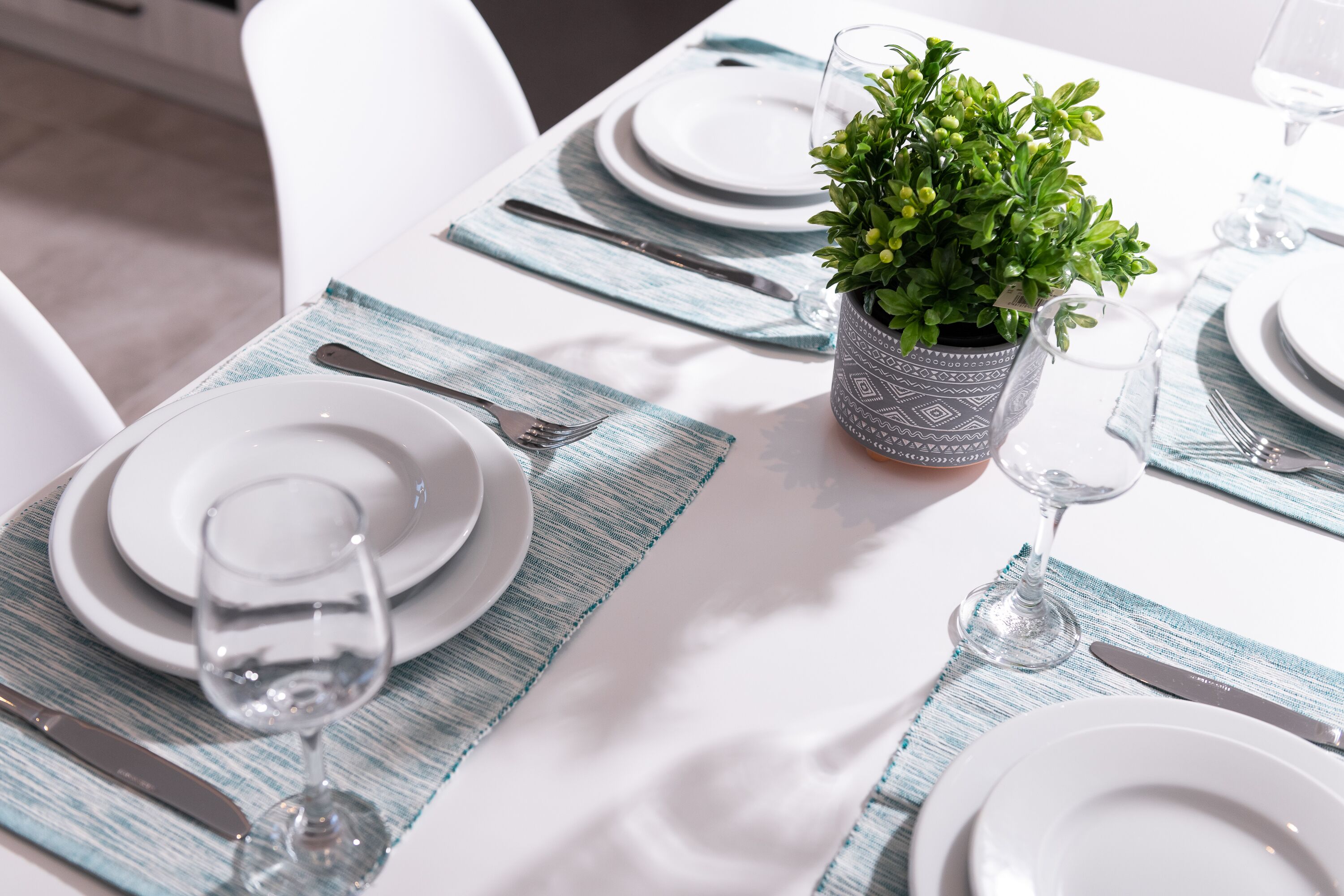 Una mesa dispuesta con platos blancos, cubiertos y un vaso de agua.