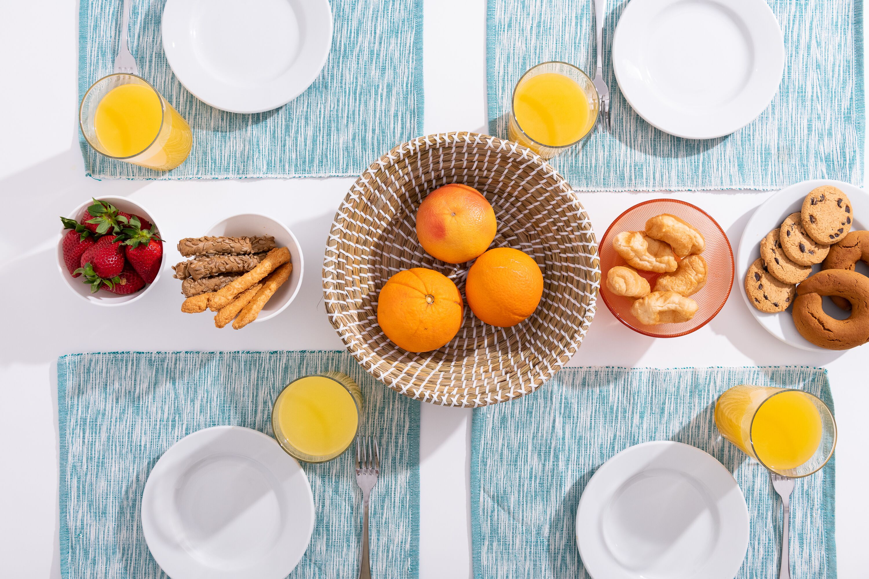A breakfast setting with plates, bowls, and glasses of orange juice.