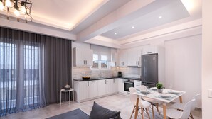 A modern kitchen with white cabinets, a black refrigerator, and a dining area with a table set for four. - Lithies Zante Living (Zakynthos)