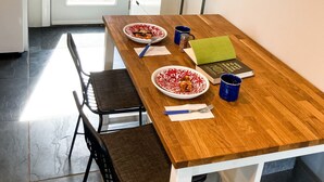 Un comedor con una mesa de madera, dos sillas, un mueble pequeño y una puerta que da al exterior.