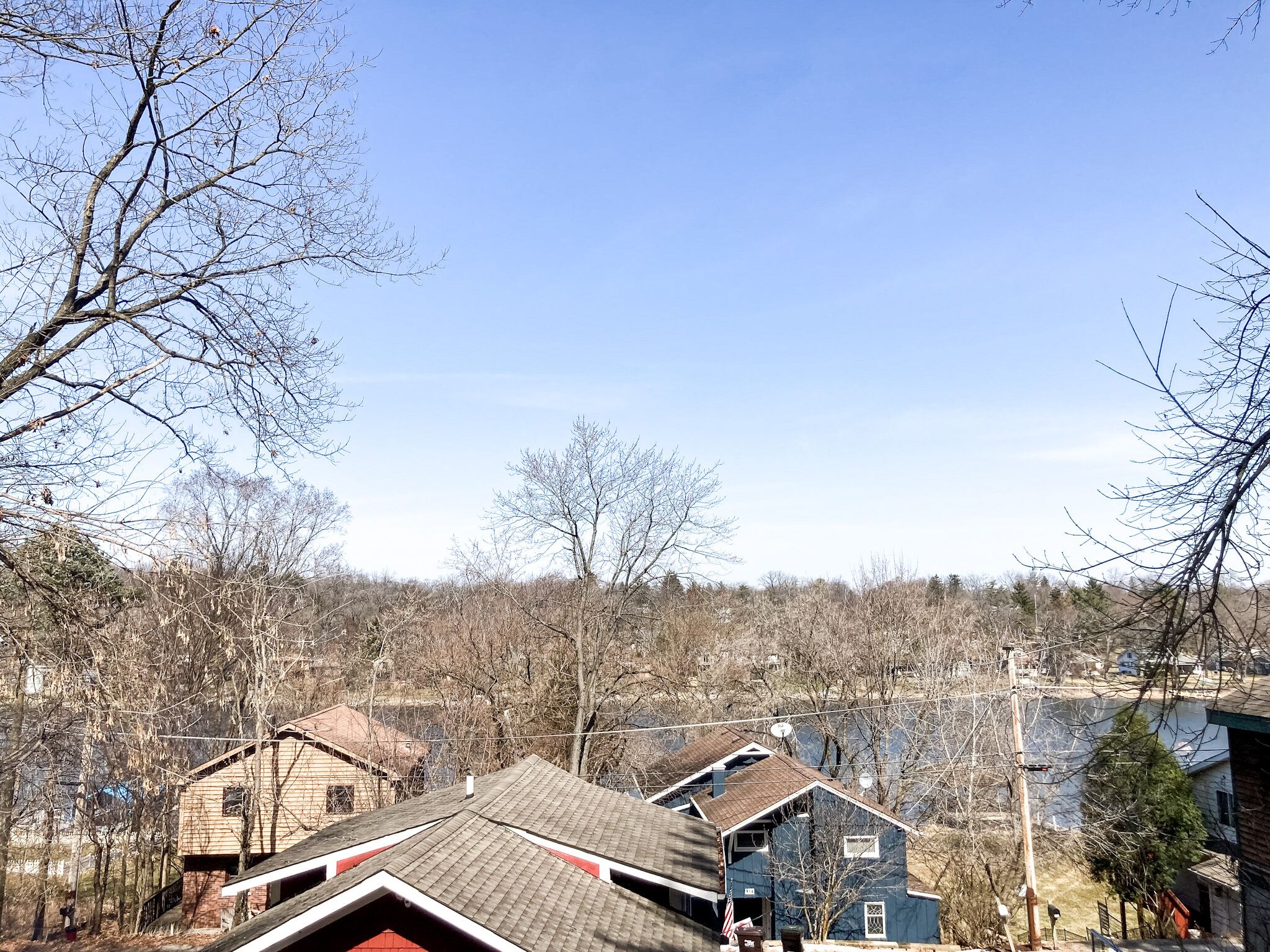 A residential area with houses, some with red roofs, and a clear blue sky.