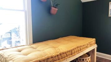A room with a bed, a dark wall, and two hanging potted plants.
