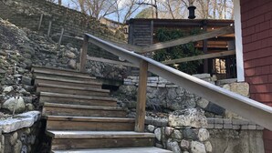 Una escalera de madera con paredes de piedra que conduce a un edificio de fachada roja.