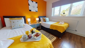 Et hotelværelse med to senge, et vindue med udsigt, et sengebord med lampe og et bakke med morgenmad.