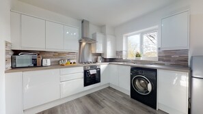 A modern kitchen with white cabinets, a built-in microwave, a gas stove, a sink, and a dishwasher. - Green View (Peterborough)