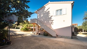 Ein zweistöckiges Gebäude mit überdachter Terrasse und Basketballkorb.