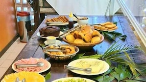 Une table de buffet proposant divers plats, notamment des fruits, des pâtisseries et un gâteau.