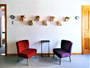 A room with two chairs, a small table, and bookshelves with books and decorative items.