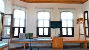 Una habitación con techo de madera, ventanas grandes, un banco, una pequeña mesa y un televisor.
