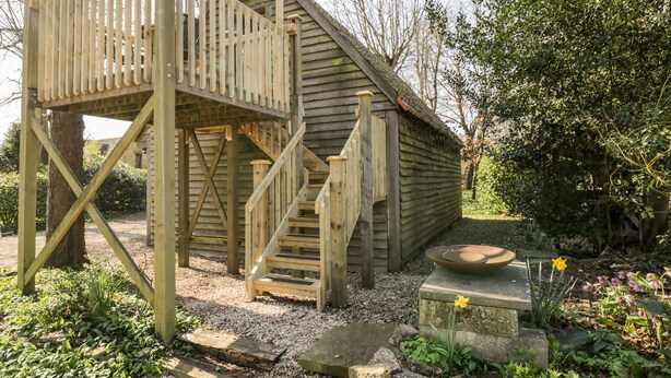 A wooden cabin with a wooden staircase leading to a deck. - Blue Bell (Corsham)