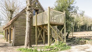 A rustic wooden cabin with a wooden deck and a stone foundation. - Blue Bell (Corsham)