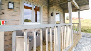 A wooden cabin with a porch, wicker furniture, and a bottle of wine. - Otters Holt (Darlington)