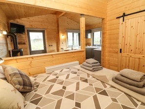 Una cabaña de madera acogedora con una cama grande, un televisor y una zona de cocina.
