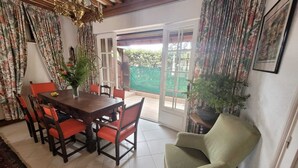 Un coin repas avec une table en bois et des chaises rouges, un fauteuil vert et un lustre.