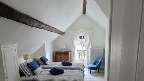 Une chambre avec deux lits, une table et une chaise.