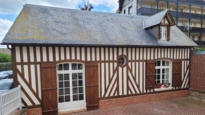 Un bâtiment de style Tudor traditionnel, doté d’un toit à forte pente, d’une charpente en bois peinte en blanc et en marron, et d’une base en briques.