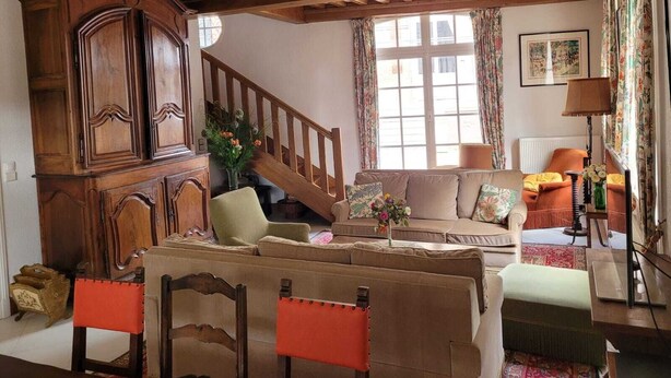 Un salon traditionnel avec un escalier en bois, un ensemble de canapés et un meuble.