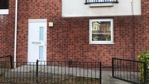 A brick building with a white door, a small window, and a balcony. - Immaculate 1-bed Apartment in Stoke-on-trent (Stoke-on-Trent)