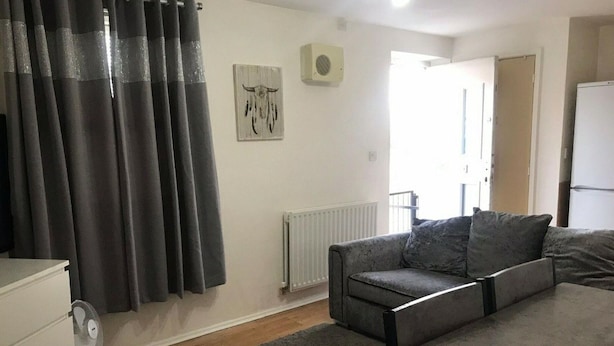 A modern living room with a grey sofa, a small table, a white dresser, and a grey rug. - Immaculate 1-bed Apartment in Stoke-on-trent (Stoke-on-Trent)