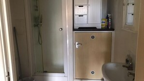 A bathroom with a shower, a sink, and a cabinet with drawers. - Immaculate 1-bed Apartment in Stoke-on-trent (Stoke-on-Trent)